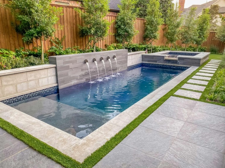 a small backyard pool with a water feature