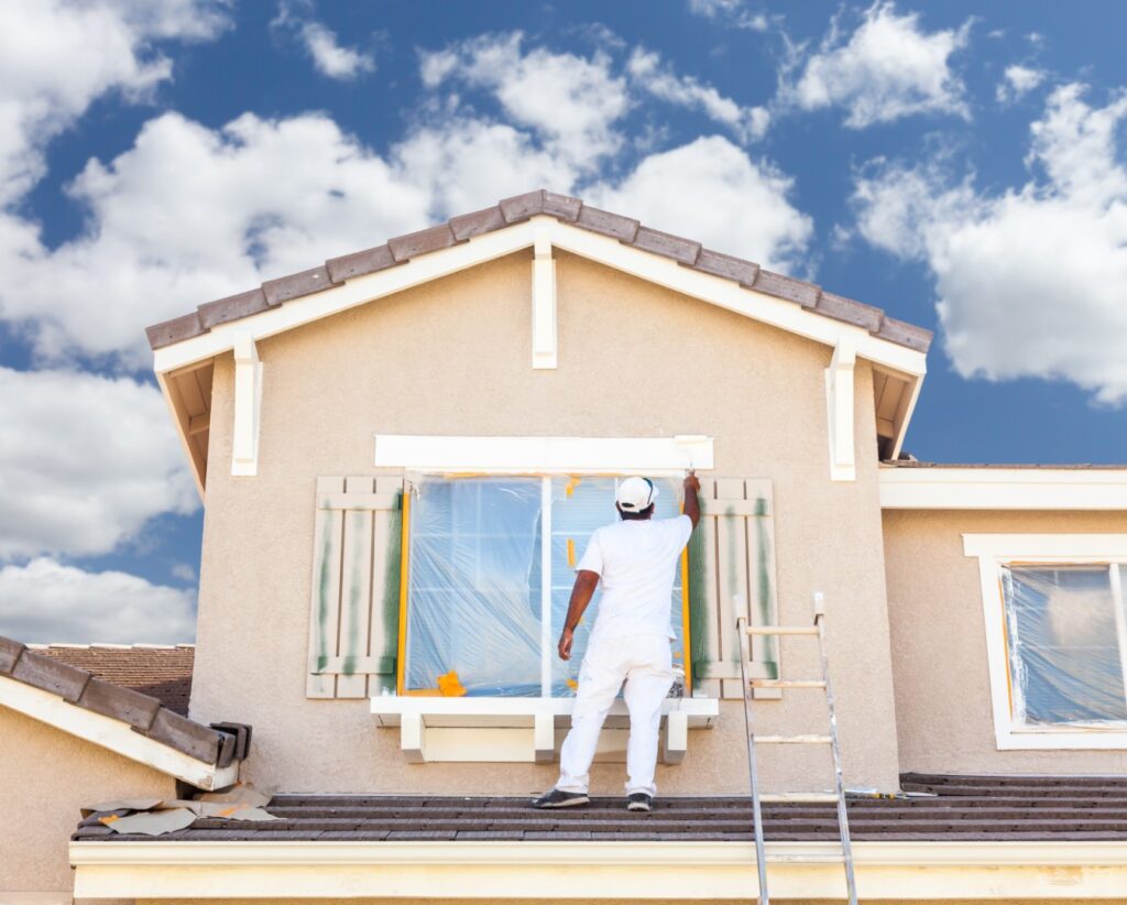 a person on a ladder painting the window of a house