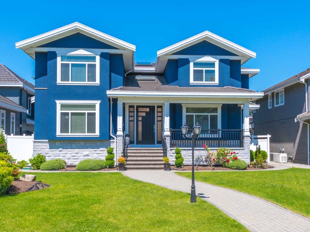 Blue house with a lawn and walkway, showcasing its protective exterior paint.