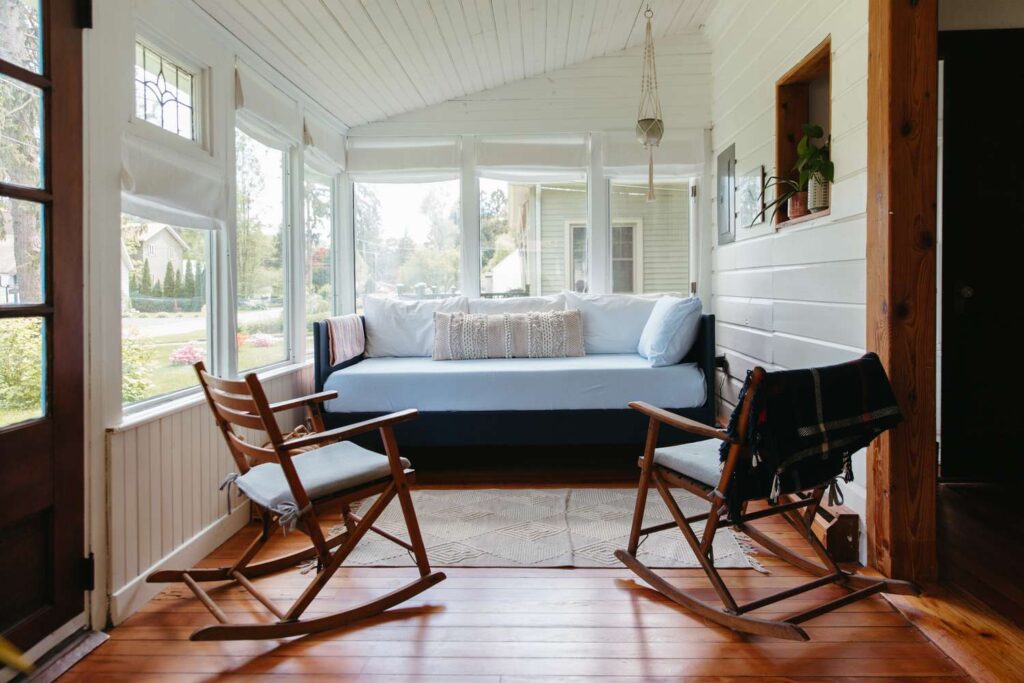 a sun room with two rocking chairs and a bed