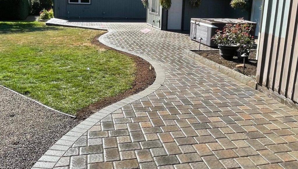 a walkway with brick pavers in front of a house